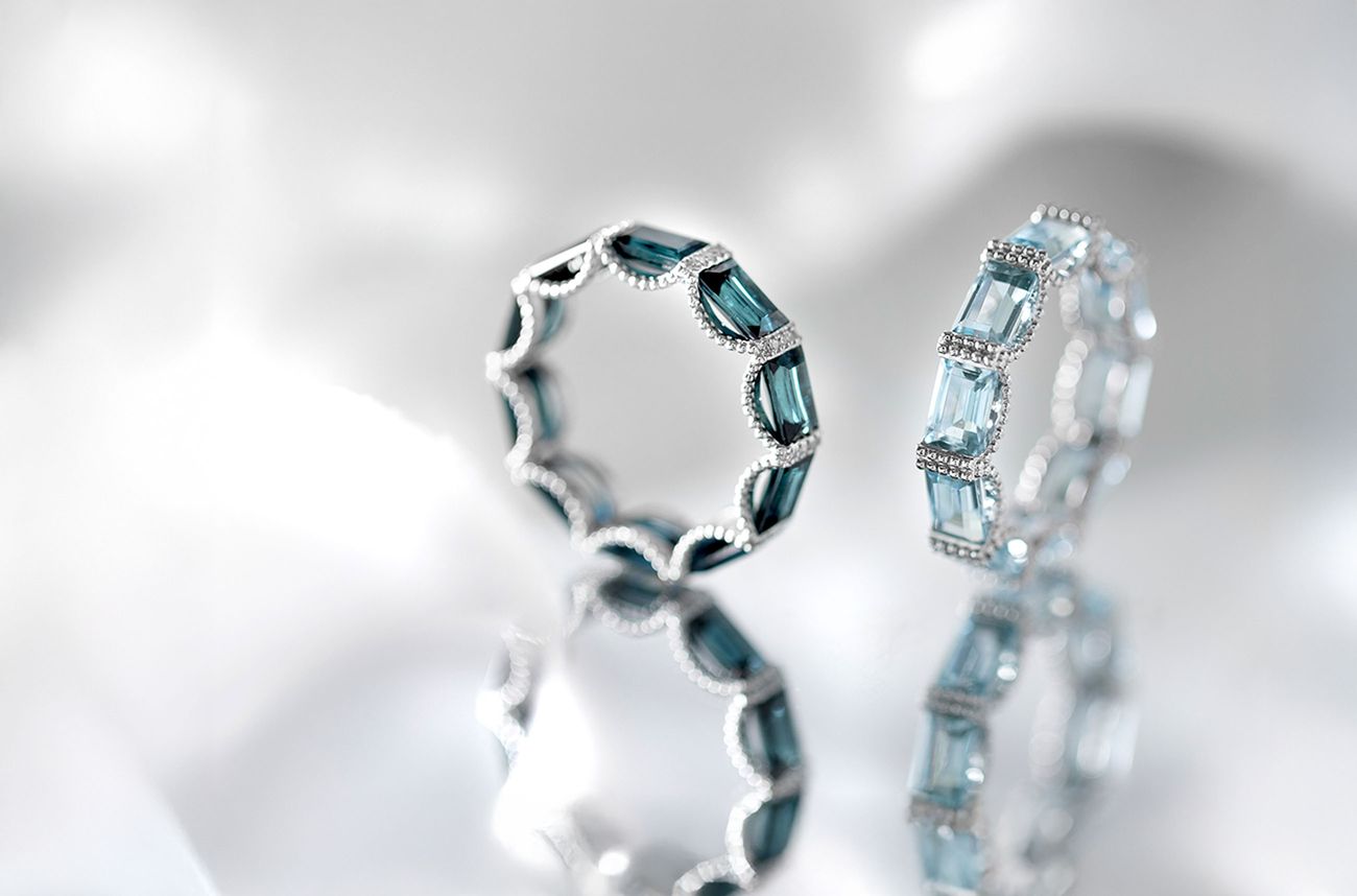 Zwei diamantbesetzte Ringe auf einer reflektierenden Oberfläche